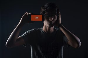 Un homme tient un smartphone avec le logo de SoundCloud à l'écran