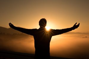 Un homme sur une colline devant un coucher de soleil