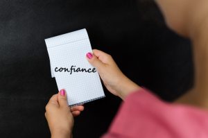 Une femme tient un carnet avec le mot confiance inscrit dessus