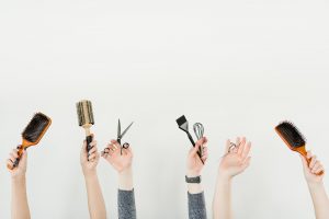 Des employés d'un salon de coiffure tiennent leurs outils de travail bien haut