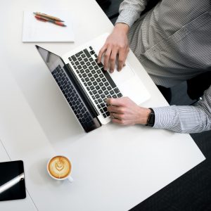 Personne utilisant un ordinateur portable sur une table en bois blanc