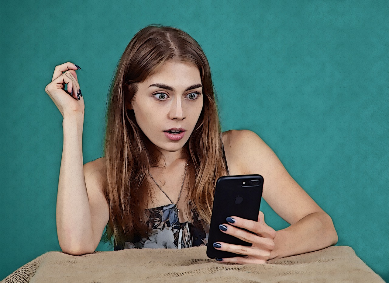 Jeune femme surprise devant son téléphone cellulaire