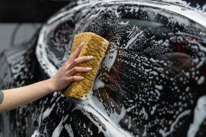 Photo d'une personne nettoyant la vitre d'une voiture noire