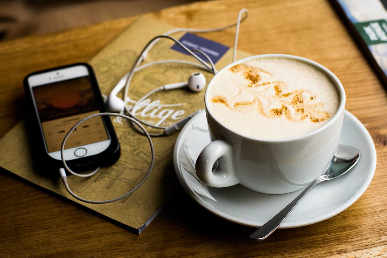 Un café latté à côté d'un téléphone cellulaire avec un balado