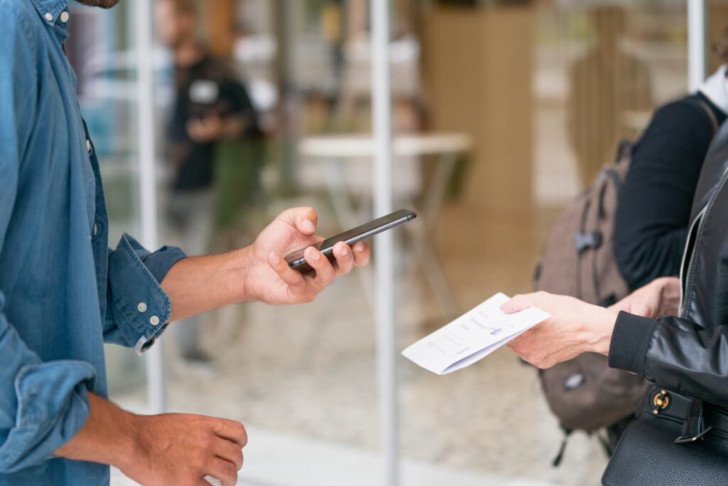 Quelqu'un tend un bout de papier qu'un personne scanne avec son téléphone