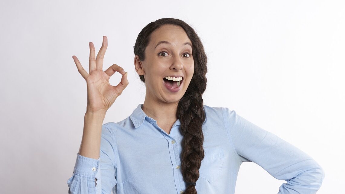 Une jeune femme fait un signe en guise de satisfaction avec les doigts