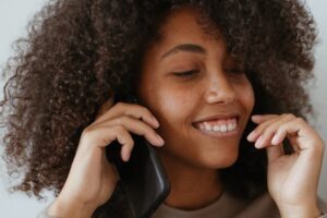 Une jeune femme avec un pull marron parle au téléphone