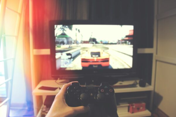 Quelqu'un tenant une manette Sony PS3 devant un moniteur à écran plat sur lequel on aperçoit une scène de Grand Theft Auto