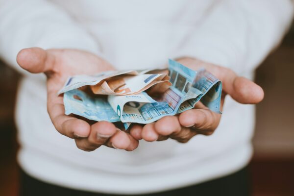 Une personne tend ses mains remplies de billets de banque lors d'une levée de fonds