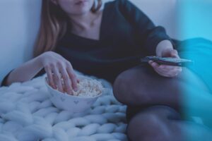 Femme tenant une télécommande tout en mangeant du pop-corn