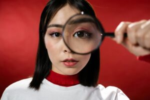 Une femme regarde à travers la lentille grossissante d'une loupe