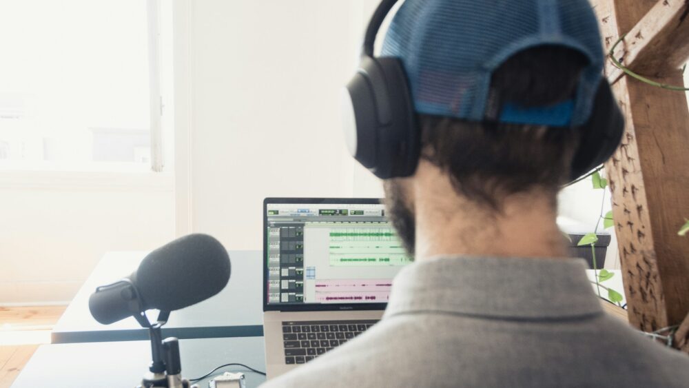 Un podcasteur devant un micro et un écran d'ordinateur