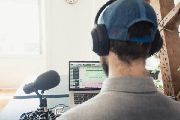 Un podcasteur devant un micro et un écran d'ordinateur